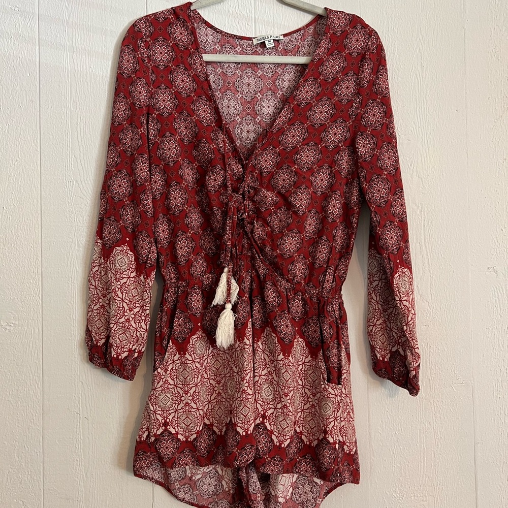 Red printed long sleeve romper. Sinched tie up detail in front with tassels